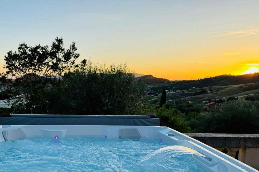 A private hot tub with bubbling water at a luxury villa in Sicily, overlooking the countryside and a vibrant sunset.