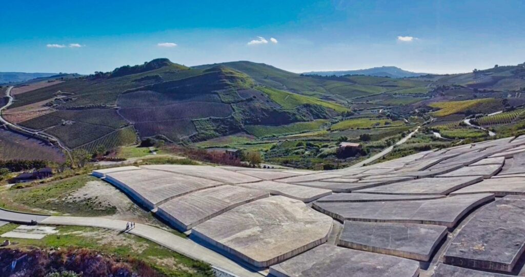 Aerial view of the Cretto di Burri in Gibellina, Sicily, featuring large concrete slabs set within a scenic landscape of vineyards and hills.