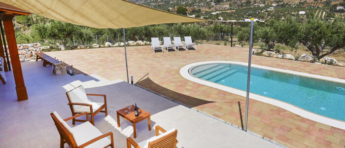 Spacious poolside terrace with shaded seating, sun loungers, and panoramic mountain views at Villa Pietra Dorata, Sicily.